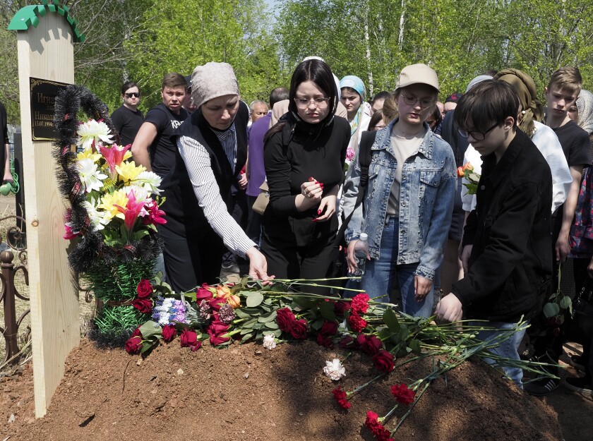 Relatives, friends and school children lay flower at the grave of Elvira Ignatieva, an English language teacher who was killed in a shooting at a school on Tuesday, during her funeral in Kazan, Russia, Wednesday, May 12, 2021. Russian officials say a gunman attacked a school in the city of Kazan and Russian officials say several people have been killed. Officials said the dead in Tuesday's shooting include students, a teacher and a school worker. Authorities also say over 20 others have been hospitalised with wounds. (AP Photo/Dmitri Lovetsky)