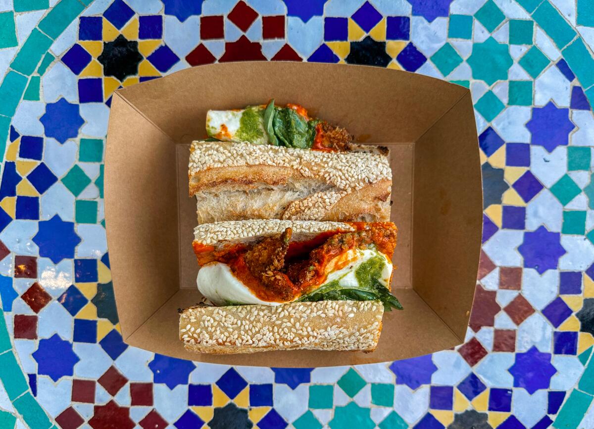 The Spicy P, a chicken parm sandwich dressed in vodka sauce, in a container on a colorfully patterned table top.