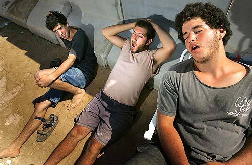 Protesters rest against a concrete barrier at the Kissufim Crossing just outside the Green Line in Gaza after an all-night 15-mile walk from a checkpoint outside the closed military zone.