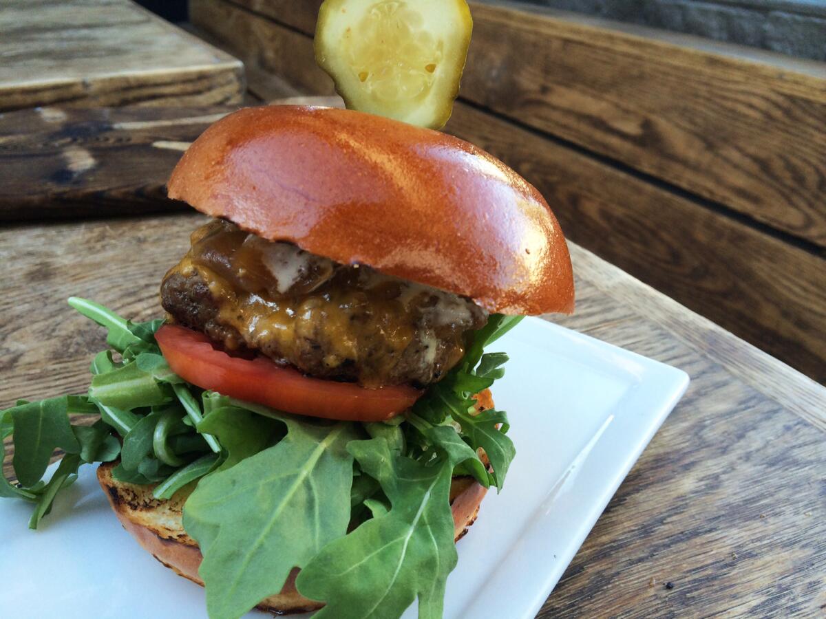 The happy hour burger features balsamic onions, cheddar cheese, arugula and tomato on a brioche bun.