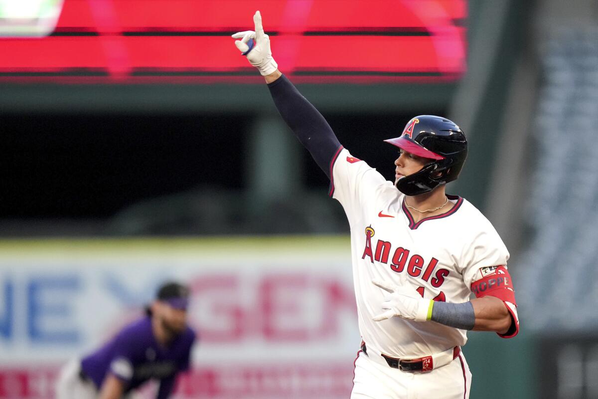 Logan O'Hoppe gestures after hitting a home run while wearing an Angels home uniform and righty batting helmet