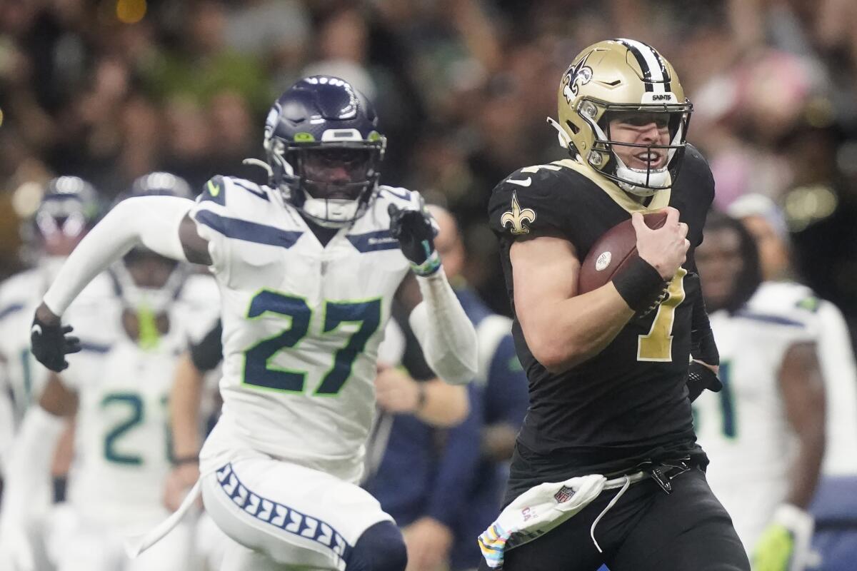 New Orleans Saints' Taysom Hill heads to the end zone for a 60 yard rushing touchdown as Seattle Seahawks' Tariq Woolen pursues during an NFL football game in New Orleans, Sunday, Oct. 9, 2022. (AP Photo/Gerald Herbert)