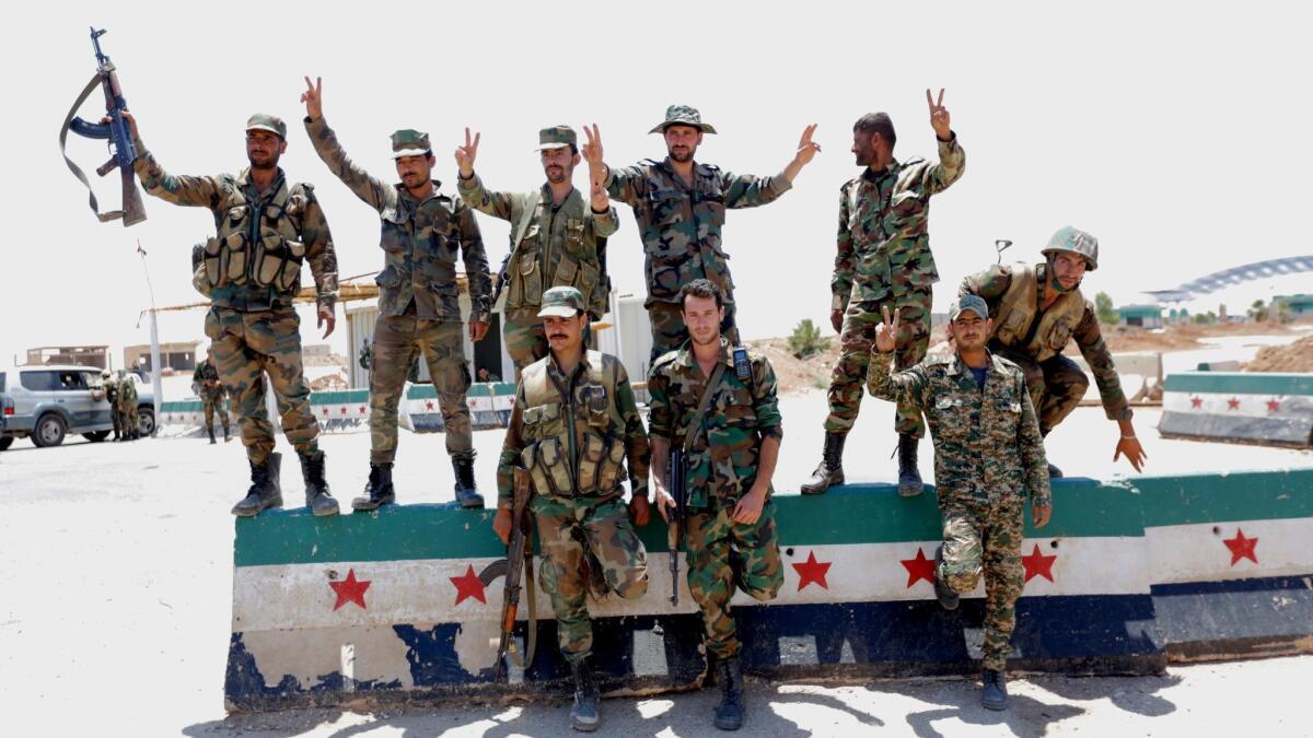 Syrian soldiers flash the victory sign at the Nassib border crossing near Deraa, Syria, on July 7, 2018.