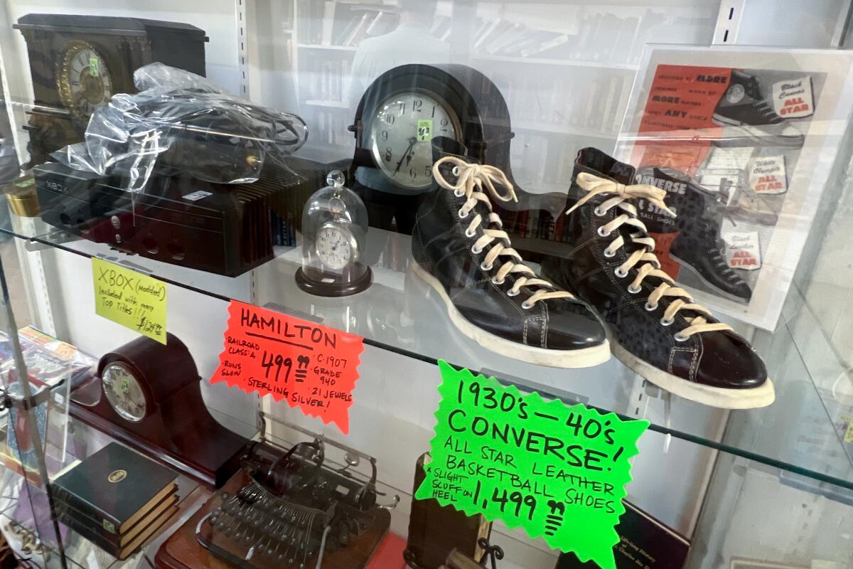 Clocks, leather Converse basketball shoes and more on shelves at a thrift store.