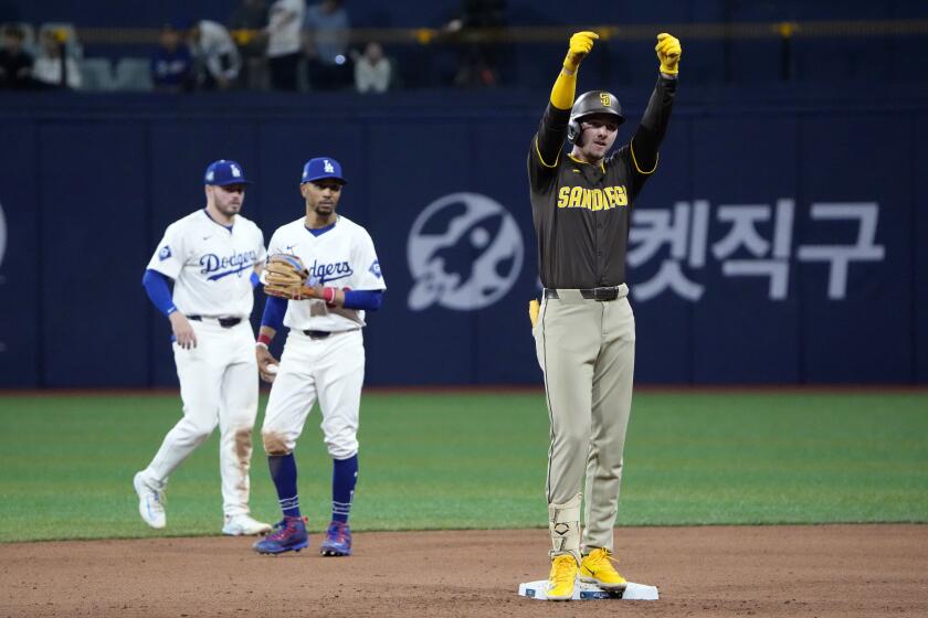 San Diego Padres' Jackson Merrill, right, gestures after hitting a double by Los Angeles Dodgers' Gavin Lux, left, and Mookie Betts stand in the background during the fifth inning of a baseball game at the Gocheok Sky Dome in Seoul, South Korea Thursday, March 21, 2024, in Seoul, South Korea. (AP Photo/Ahn Young-joon)