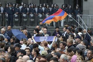 La policía bloquea un edificio del gobierno mientras manifestantes con una bandera armenia marchan contra el primer ministro, Nikol Pashinyan, en Ereván, Armenia, el domingo 26 de mayo de 2024. Los inconformes han protestado durante semanas, desde que el gobierno devolvió a Azerbaiyán cuatro pueblos fronterizos. (Stepan Poghosyan/Photolure via AP)
