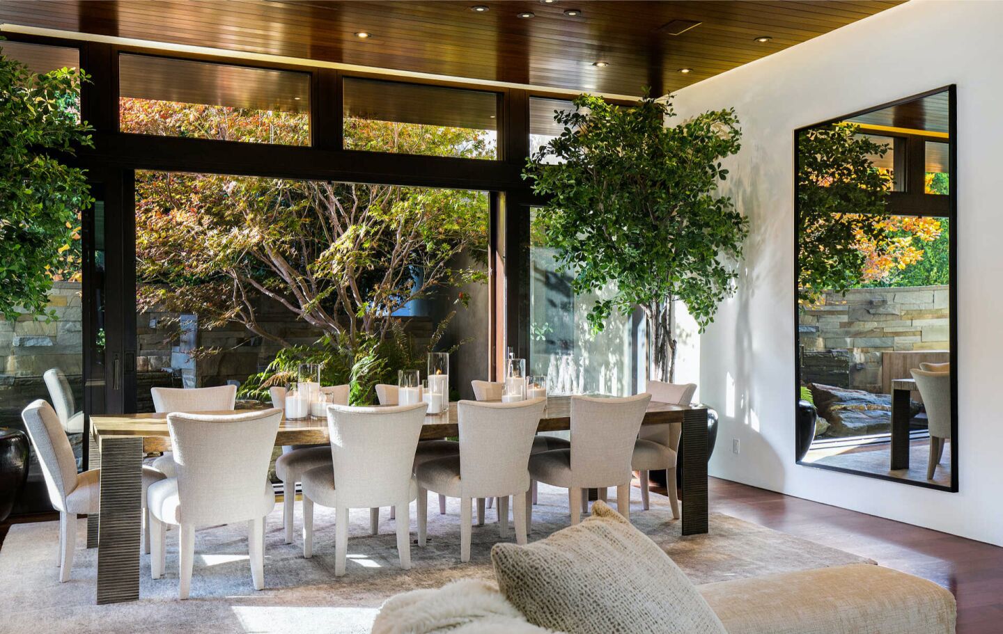 The furnished dining room with big windows overlooking trees.