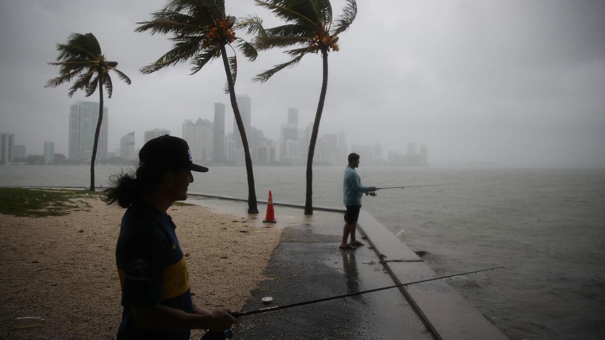 Walter Augier, left, and Jhon M. fish as rain and wind are whipped up by Tropical Storm Gordon on Monday in Miami.