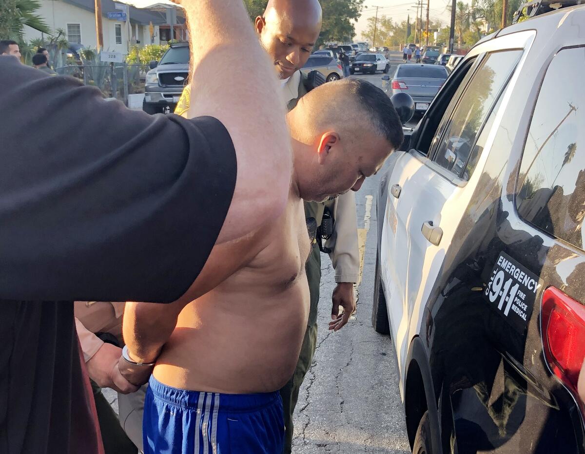Sheriff's deputies place a shirtless man in handcuffs.