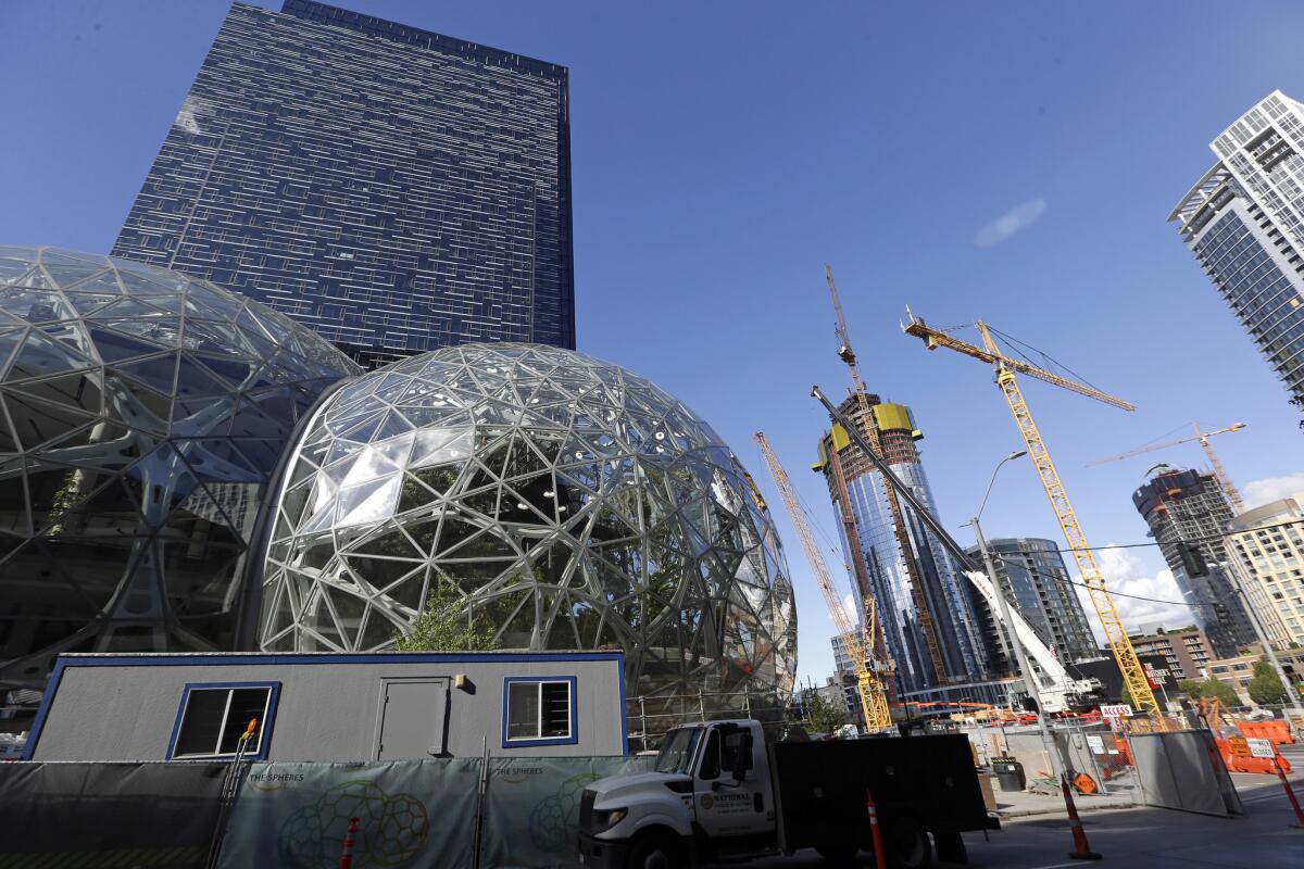 Large spheres take shape in front of an existing Amazon building, as new construction continues across the street.