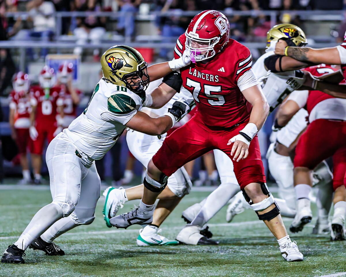 Offensive tackle Lucas Rhoa of Orange Lutheran High holds his grond as a defender sticks his hands in his face and chest.