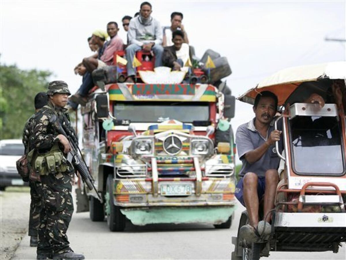 Army troopers man a checkpoint near the hillside grave in Ampatuan, Maguindanao province, southern Philippines on Wednesday Nov. 25, 2009. Philippine President Gloria Macapagal Arroyo placed two southern provinces under a state of emergency, giving security forces free hand to pursue gunmen who killed at least 52 people in one of the country's worst election massacres. (AP Photo/Aaron Favila)