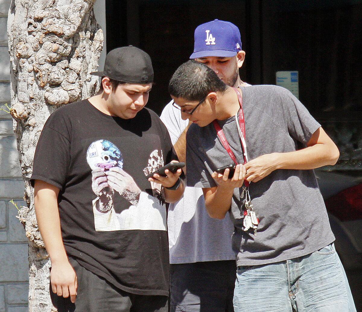 Christian Perez, Marcus Morales, and Oscar Sanchez, of Glendale, check out their cellphones looking for Pokemon Go landmarks.