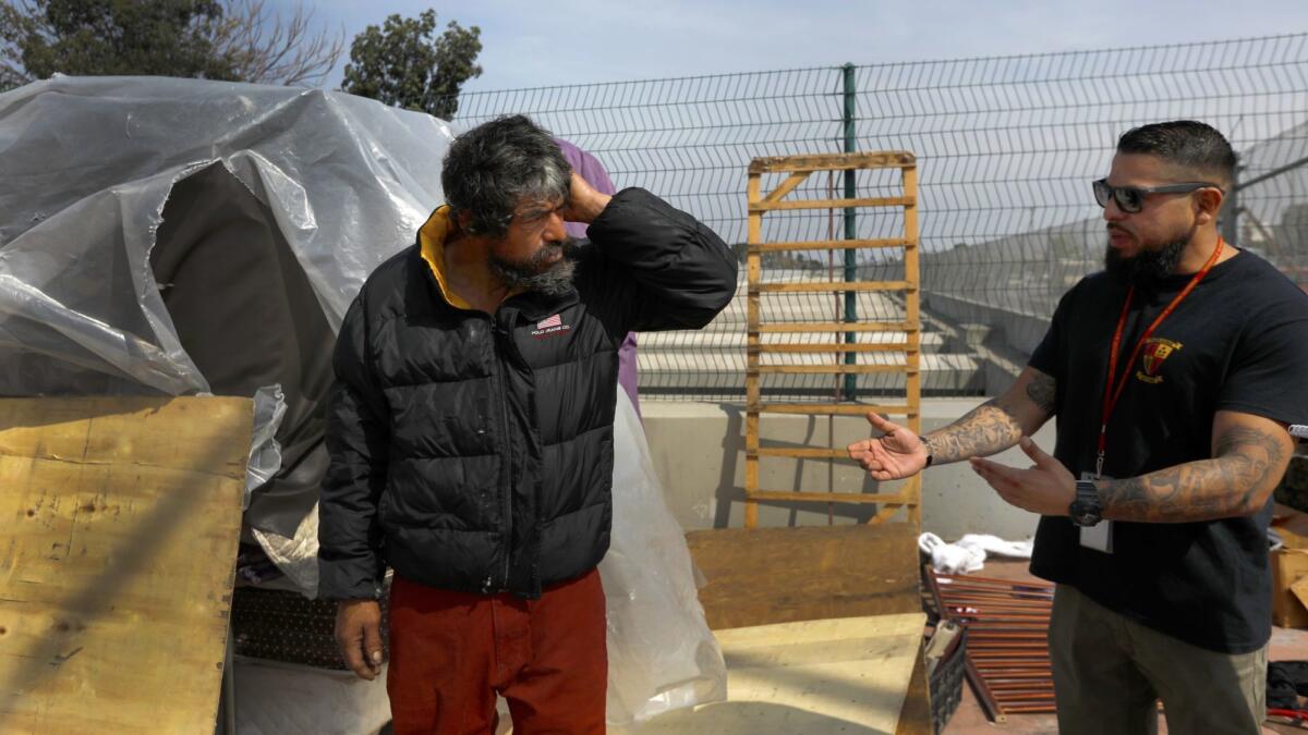 Adrian Tafoya, right, with the Homeless Outreach Program Integrated Care System talks to Jesus (no last name given) in Compton. In L.A. County, the Department of Mental Health has accumulated nearly $900 million in unspent funds meant to help treat the mental ill.