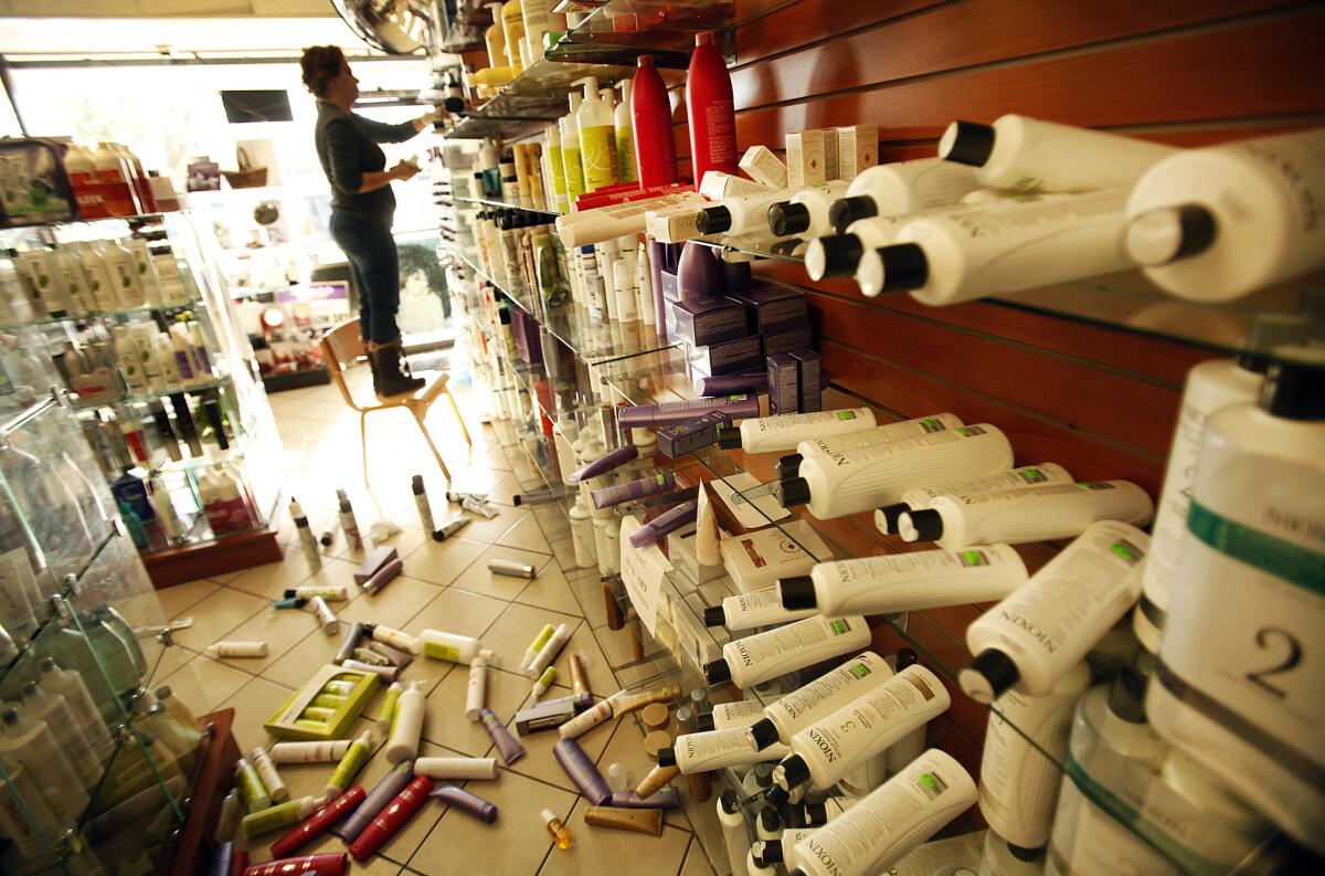 Roya Alagh, manager of Sherman Oaks Beauty Center on Ventura Boulevard in Sherman Oaks, cleans up hair care products knocked to the floor by an earthquake that struck Los Angeles about 6:25 a.m. Monday.