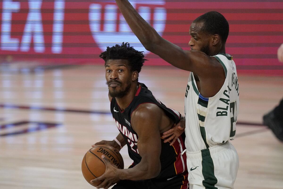 Miami Heat's Jimmy Butler, left, drives against Milwaukee Bucks' Khris Middleton.