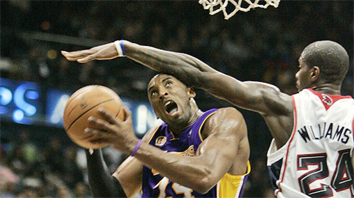 Despite a hand injury, the Lakers' Kobe Bryant drives to the basket during the second quarter of a basketball game in Atlanta.