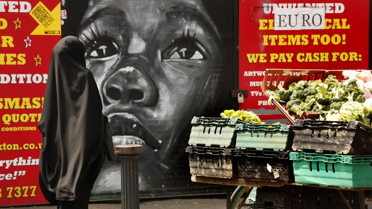 A woman walks past produce for sale in the Brixton district of London, a multiethnic community.