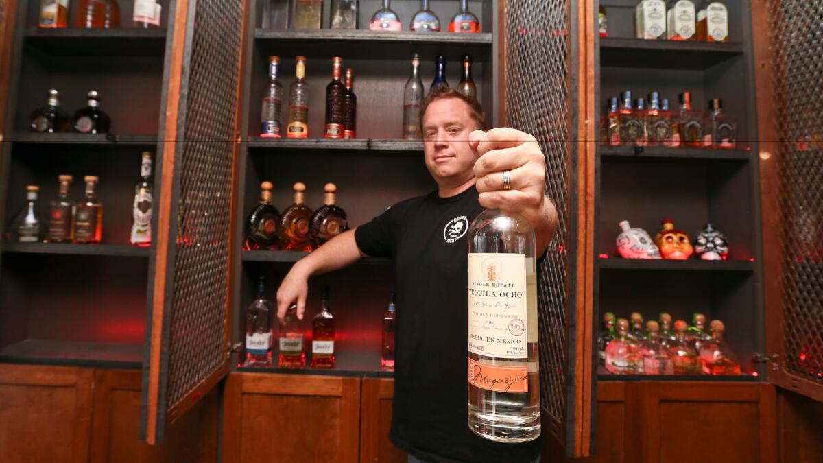 Frank Miller shows off some of the tequila collection at The Blind Burro in San Diego, where the tequila prices can change every five minutes based on demand.