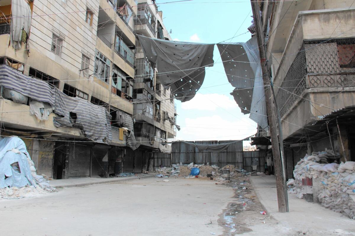 Curtains, meant to deter the ubiquitous snipers along the so-called Passageway of Death, hang between buildings in Aleppo, Syria.