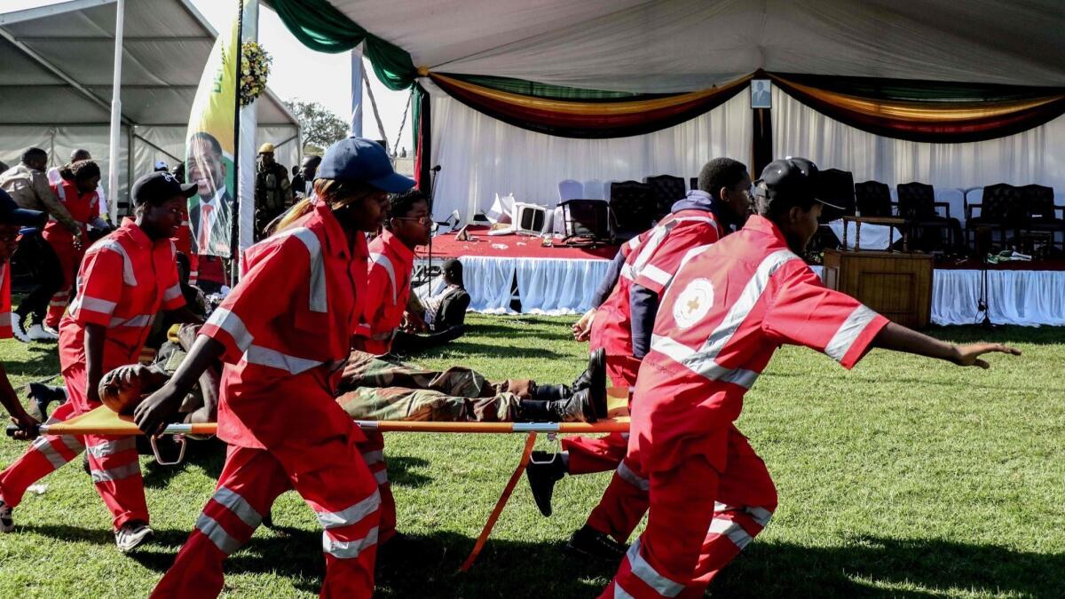 Injured people are evacuated after an explosion at the stadium in Bulawayo where Zimbabwe's president had just addressed a rally on June 23.