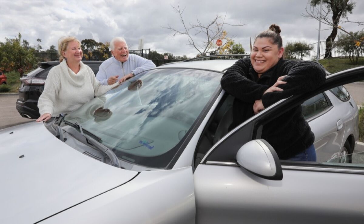 Outside the San Marcos DMV office Monday, March 16, Carla Ramirez (right) stands with her low-mileage 2002 Ford Taurus SEL she just received from Passion 4 K.I.D.S., founded by Charles and Linda Van Kessler (left) of Encinitas. Ramirez’s son Christopher, 15, has cancer.