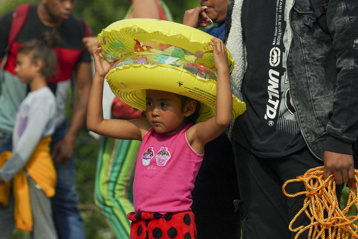 Una niña migrante sostiene flotadores del lado mexicano del río Bravo,