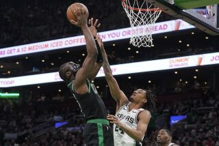 Jaylen Brown, izquierda, de los Celtics de Boston, ataca el aro con la presión defensiva de Devin Vassell, derecha, de los Spurs de San Antonio, durante la primera mitad del juego de baloncesto de la NBA, el domingo 26 de marzo de 2023, en Boston. (AP Foto/Steven Senne)