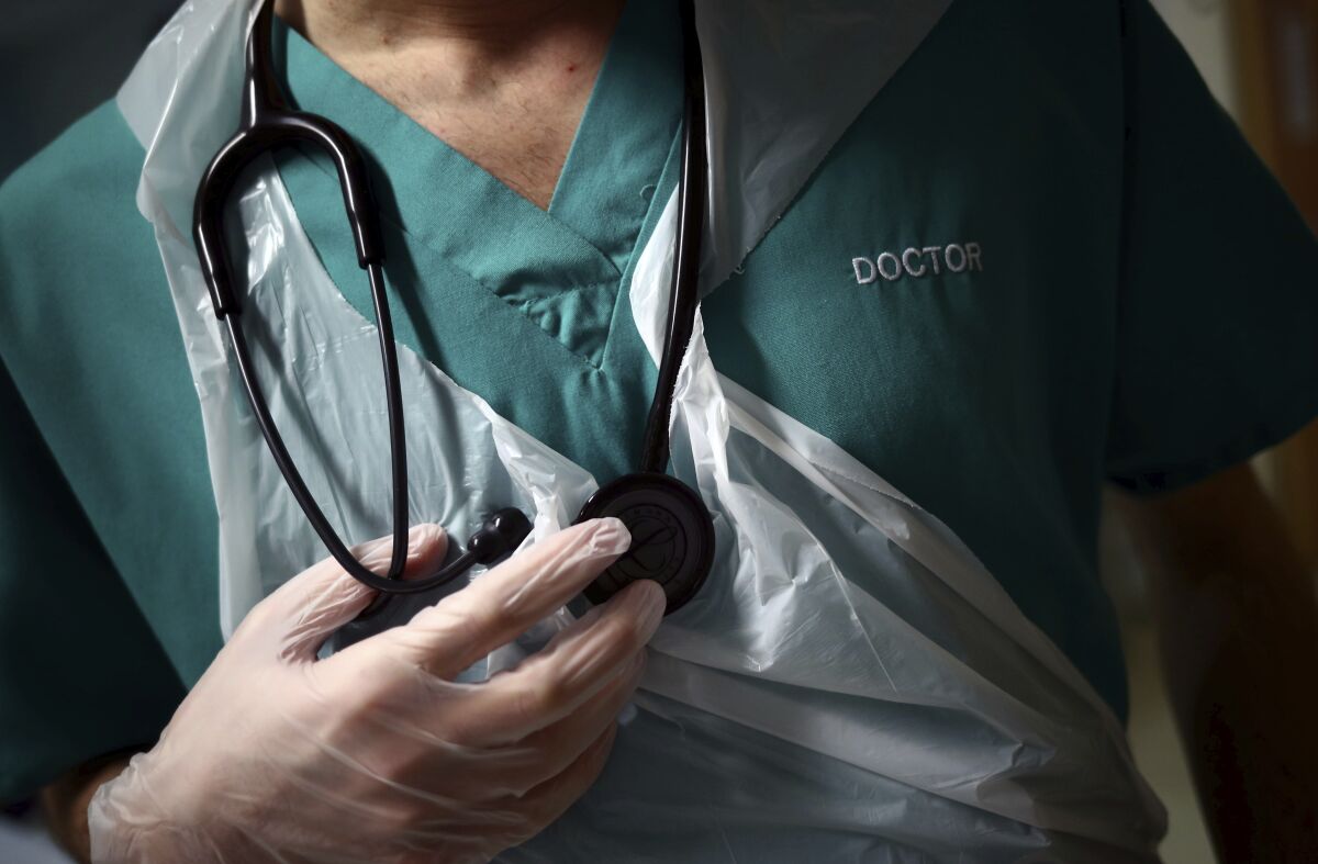 Man in medical scrubs holds stethoscope