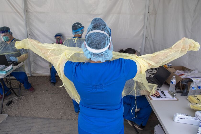 BOYLE HEIGHTS, CA - APRIL 29: Alta Med Health Services staff puts on PPE prior to COVID-19 testing on Wednesday, April 29, 2020 in Boyle Heights, CA. (Brian van der Brug / Los Angeles Times)
