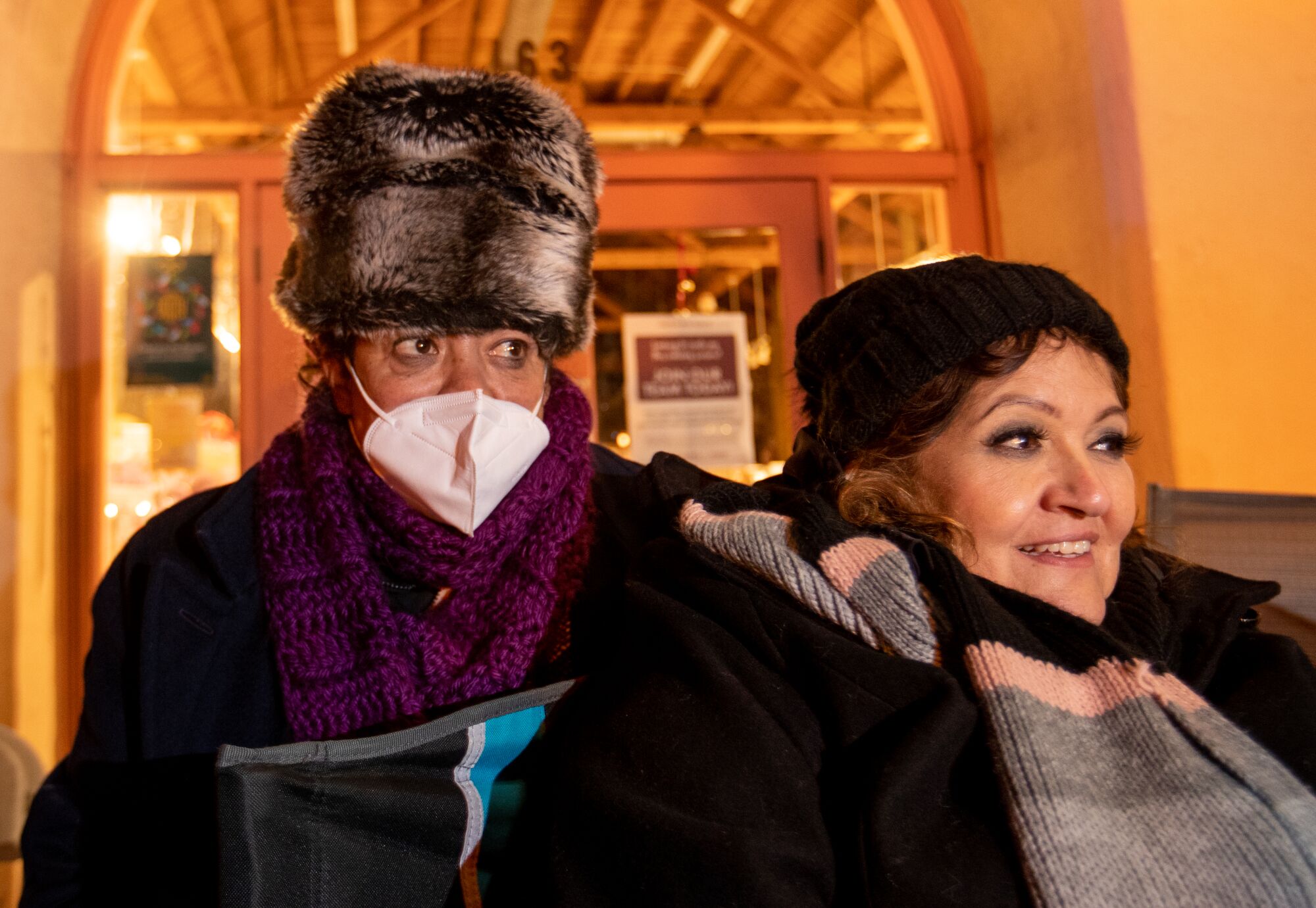 Two people stand bundled up in hats and coats.