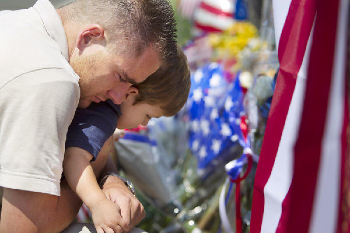 Duane Oliver of Prescott Valley, Ariz., hugs his son, Conner Oliver, 2, by a memorial for the fallen firefighters in front of Prescott Fire Station No. 7. Nineteen firefighters have died in the Yarnell Hill fire.