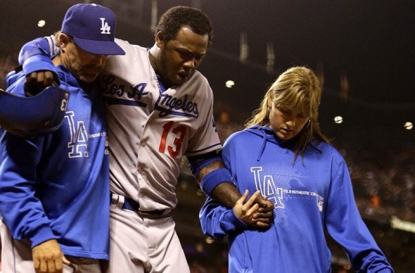 Dodgers shortstop Hanley Ramirez (13) is assisted off the field by bench coach Trey Hillman and trainer Sue Falsone after injuring his left hamstring while running the bases in the sixth inning Friday night in San Francisco.