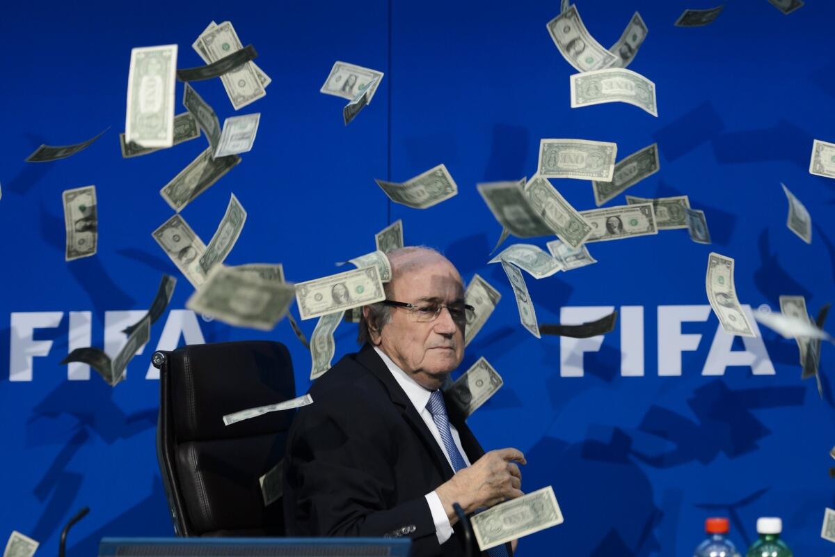 Sepp Blatter looks on with fake dollars flying around him, thrown by a protester during a news conference at FIFA headquarters in Zurich on Monday.