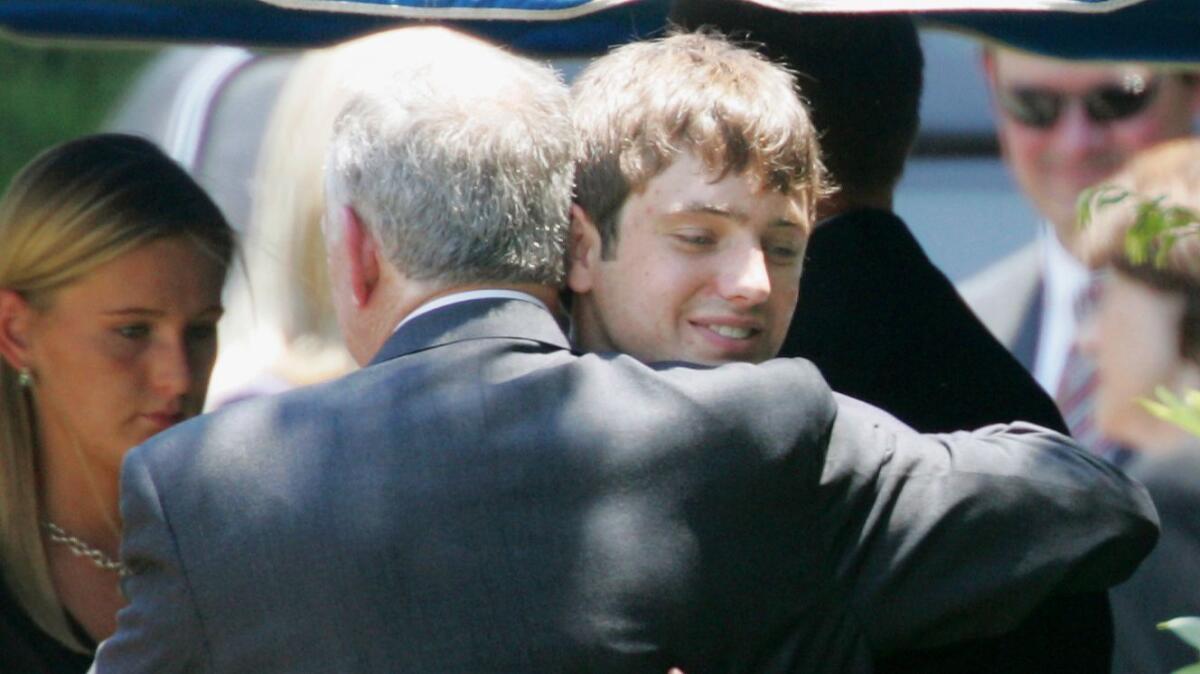 In this June 29, 2006, file photo, John Ramsey hugs his son, Burke, at the graves of his wife, Patsy, and daughter, JonBenet, during services at the St. James Episcopal Cemetery in Marietta, Ga.