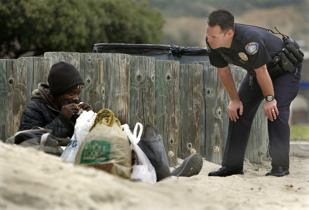 A Laguna Beach police officer speaks with a homeless man on Main Beach.