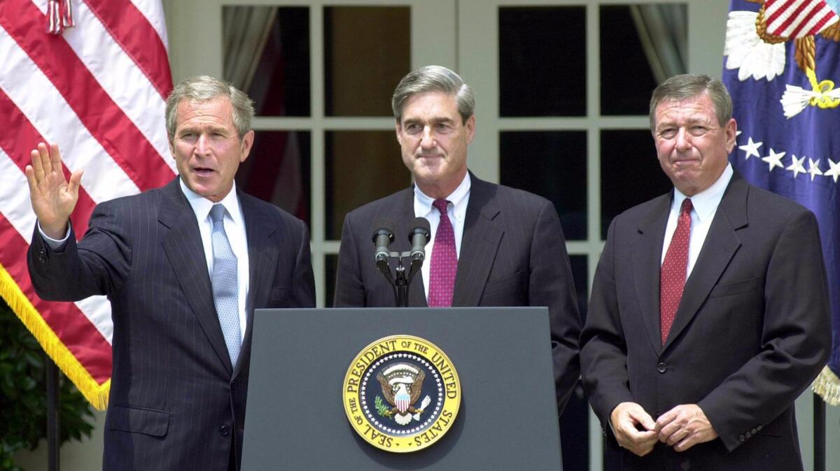 President George W. Bush waves on July 5, 2001 after announcing Robert Mueller as his choice for FBI director. On the right stands then-Atty. Gen. John Ashcroft.