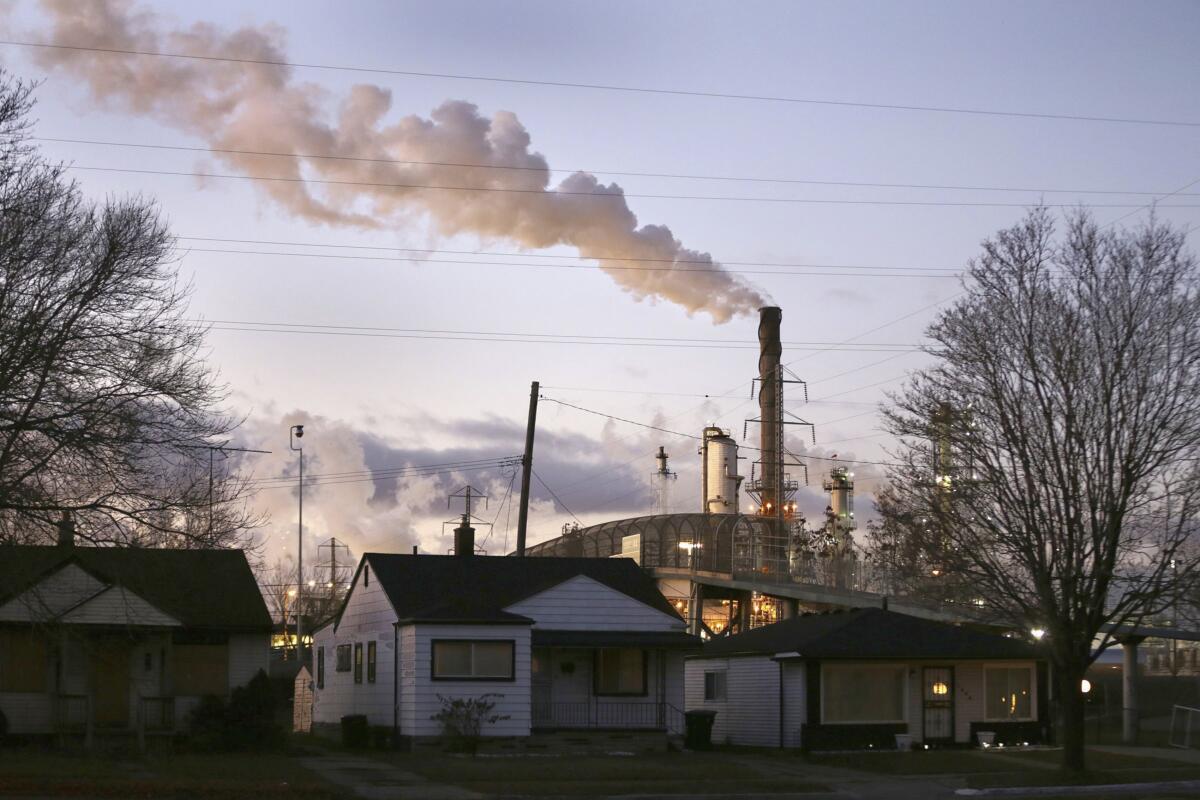 Smoke billows from a refinery near homes.