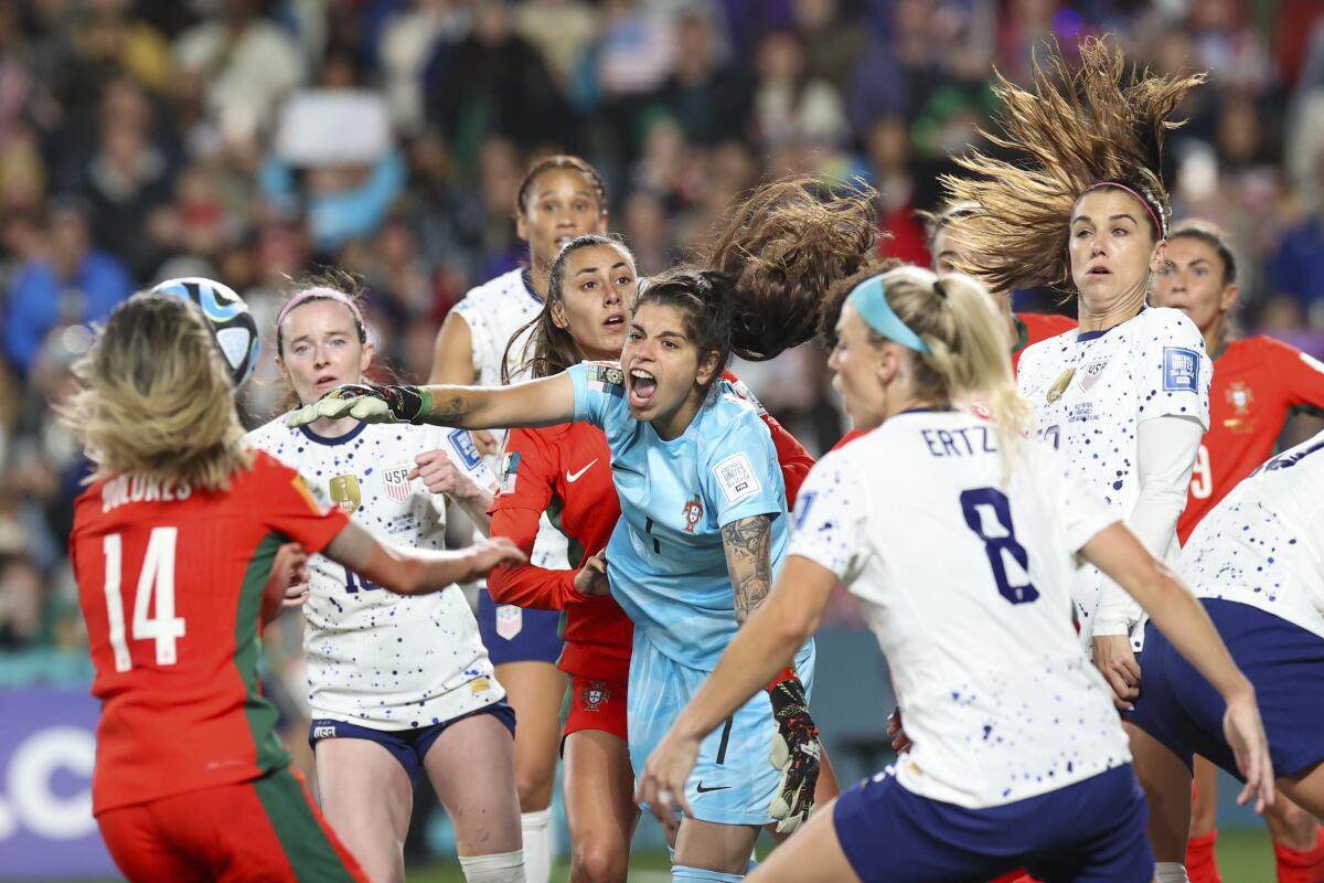 Portugal goalkeeper Ines Pereira punches the ball clear in front of a crowd of players