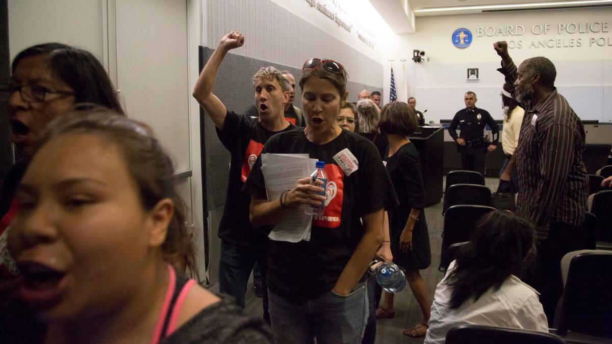 Protestors leave the L.A. Police Commission's meeting Tuesday after urging the panel to reject the LAPD's proposal to test drones.