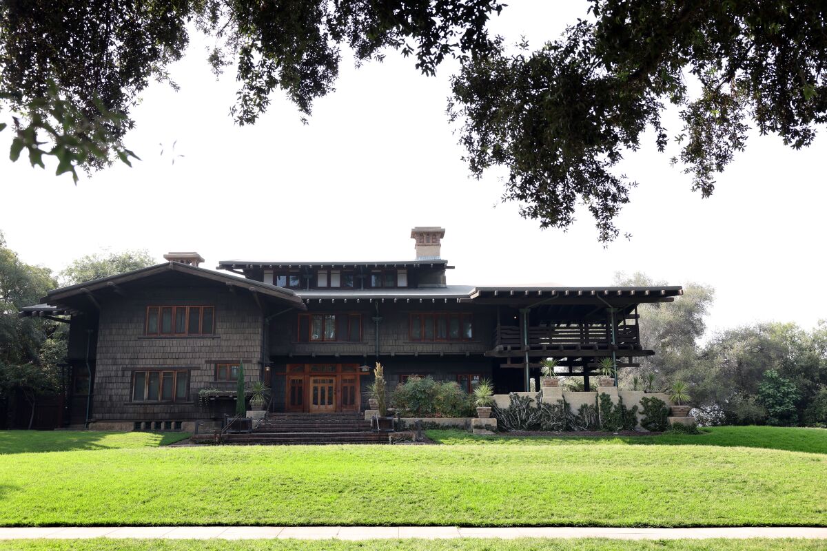 An exterior view of the Gamble House with a wide green lawn