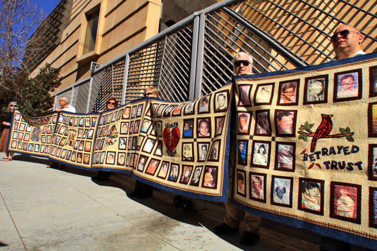 Quilts depicting victims of sexual abuse by priests are held up by victims and their supporters at the Cathedral of Our Lady of the Angels in Los Angeles.