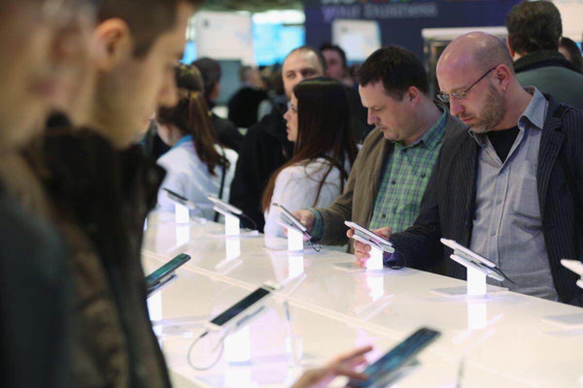 Visitors try out smartphones at the Samsung stand at the 2013 CeBIT technology trade fair on March 5 in Hanover, Germany.