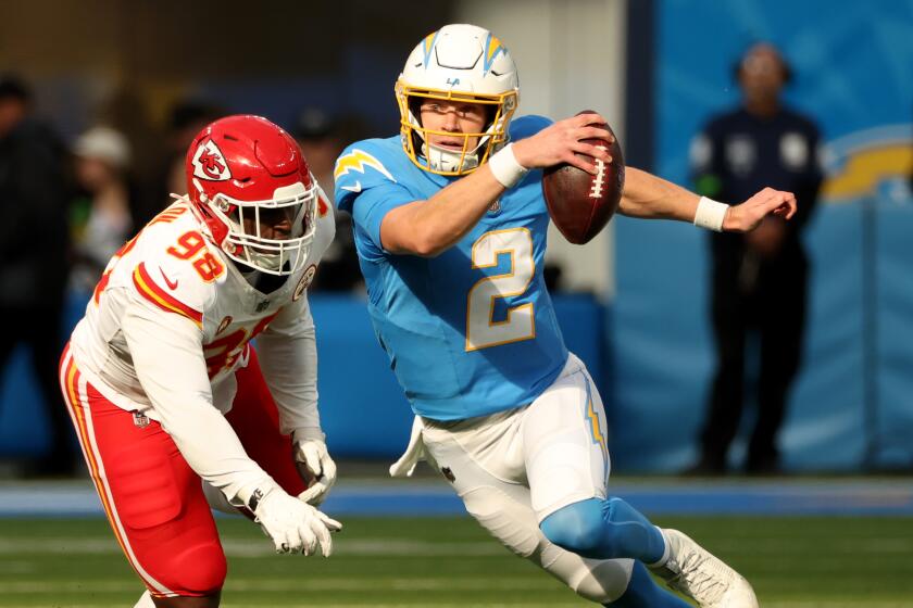 Chargers quarterback Easton Stick runs away from Chiefs defensive end Tershawn Wharton.