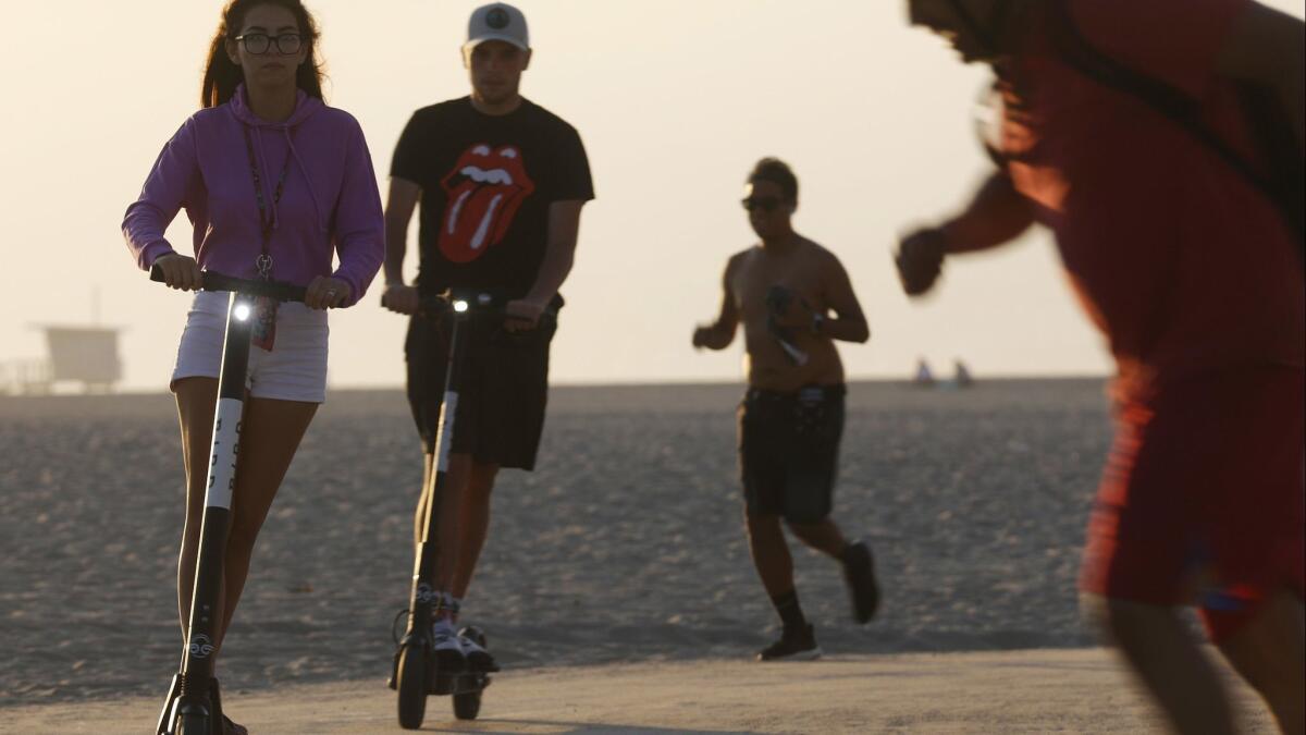 People ride Bird scooters along Venice Beach on Aug. 13.