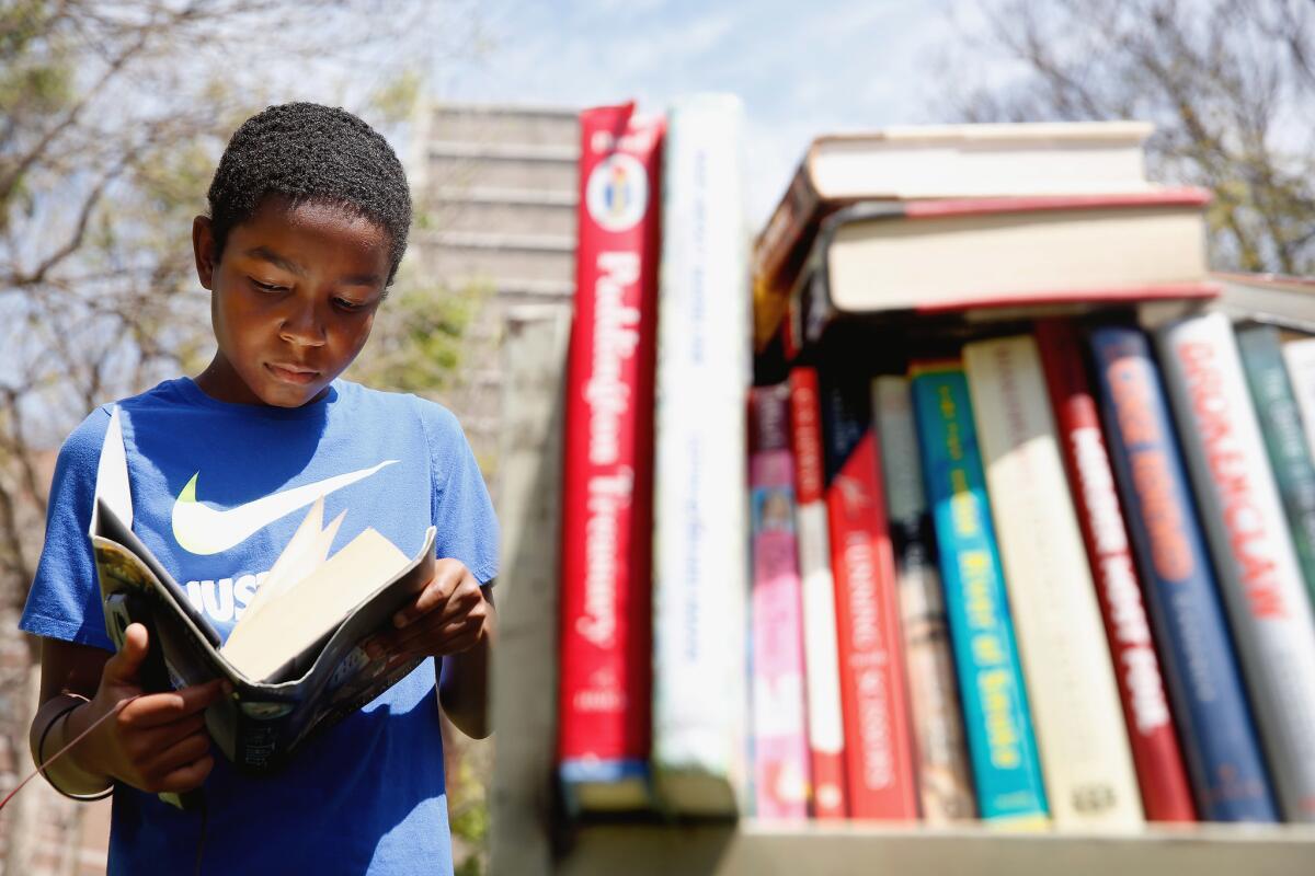Hasan Paul, 12, peeks into a book for sale during the 2019 Los Angeles Times Festival of Books.
