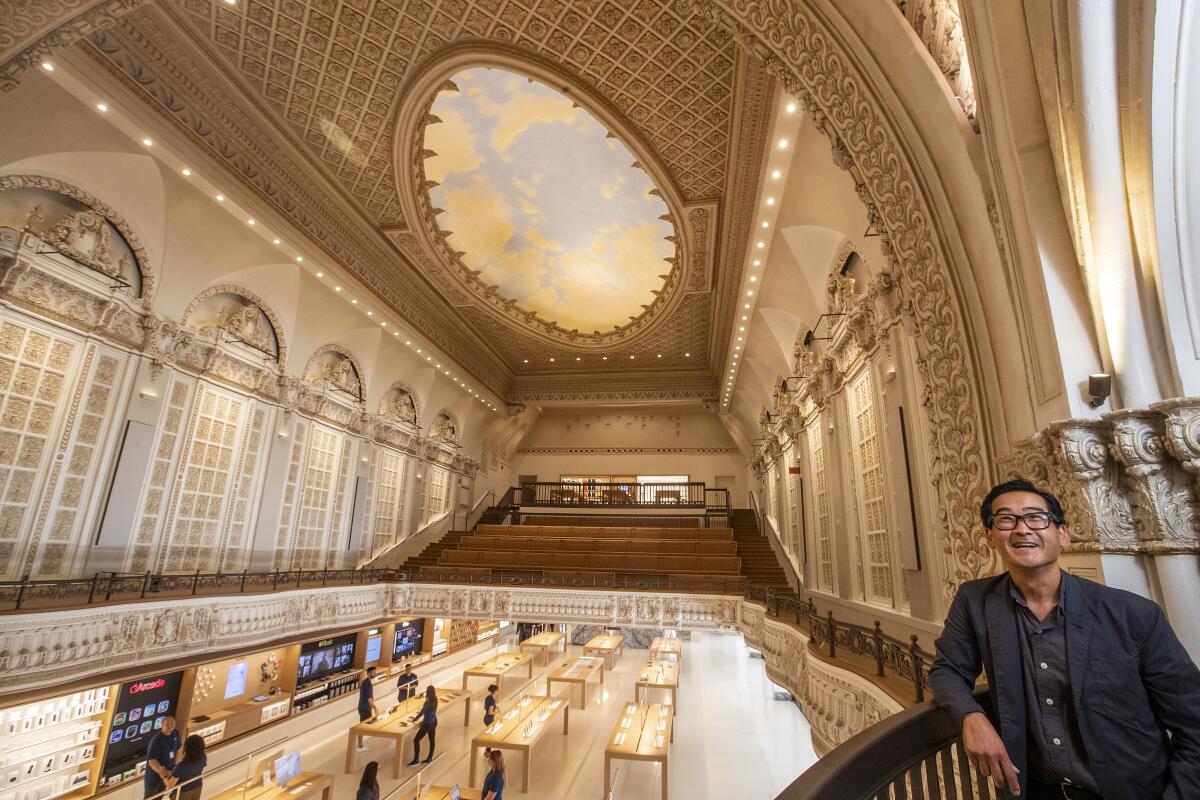 Man stands to the right with ornate building interior behind.