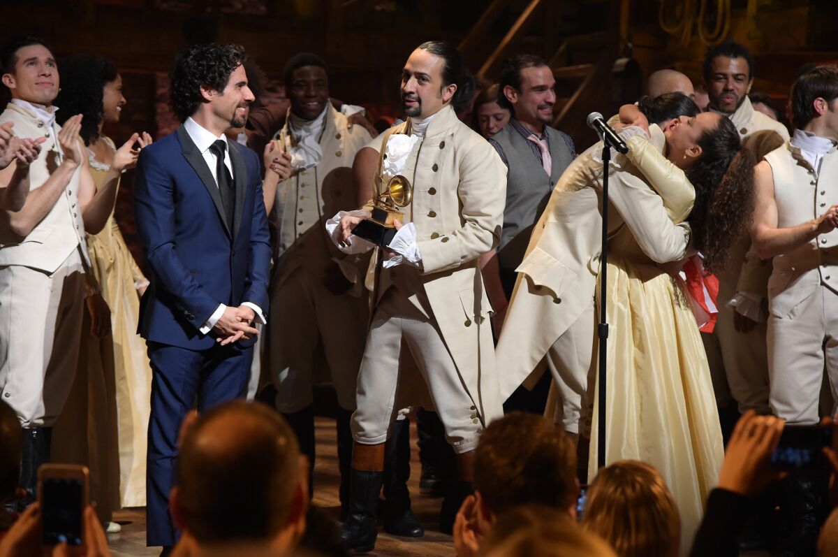 Music director Alex Lacamoire, left, and actor-composer Lin-Manuel Miranda and the cast of "Hamilton" celebrate on stage after receiving as Grammy award