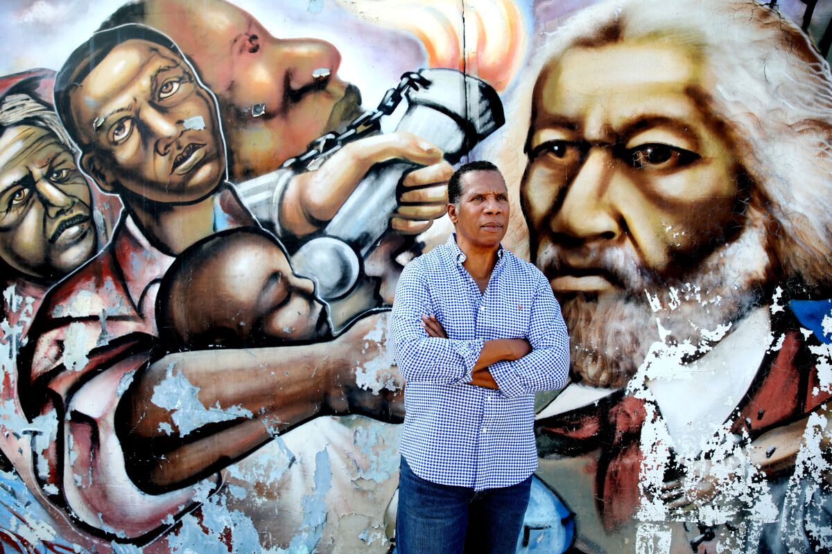A man stands in front of a mural