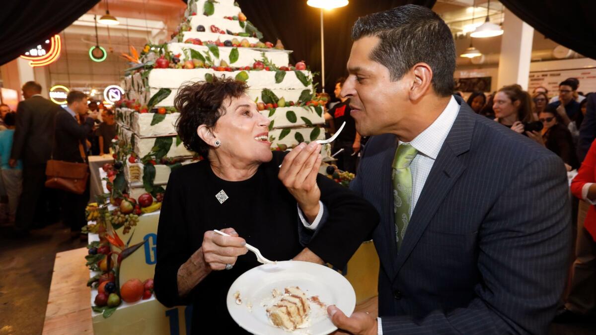 Grand Central Market owner Adele Yellin, left, shares a piece of cake with Assemblyman Miguel Santiago (D-Los Angeles) during Grand Central Market's 100th anniversary celebration on Friday.